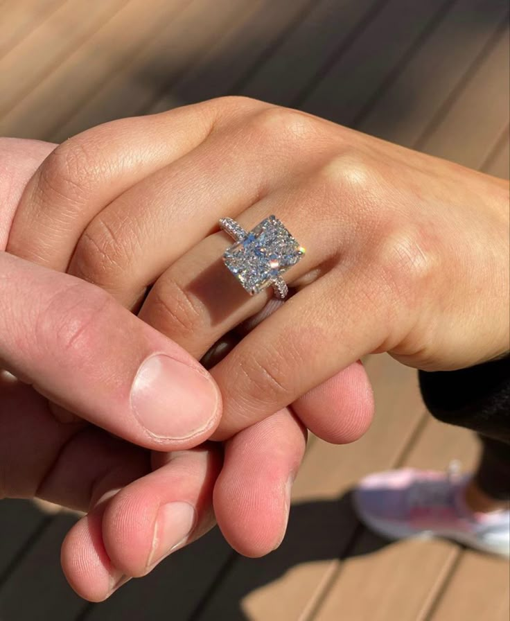 a man and woman holding each other's hand with a diamond ring on their finger