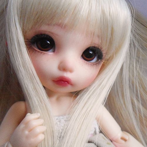 a doll with long blonde hair and big eyes is posing for the camera while wearing a dress