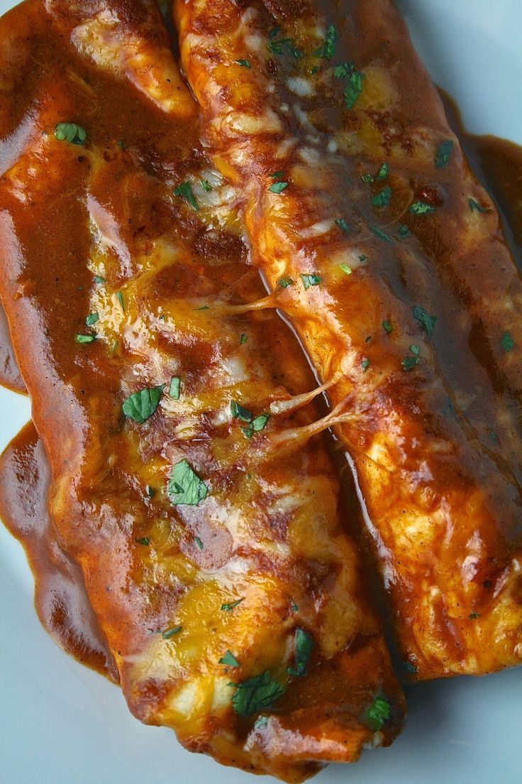 two pieces of meat covered in sauce on a white plate