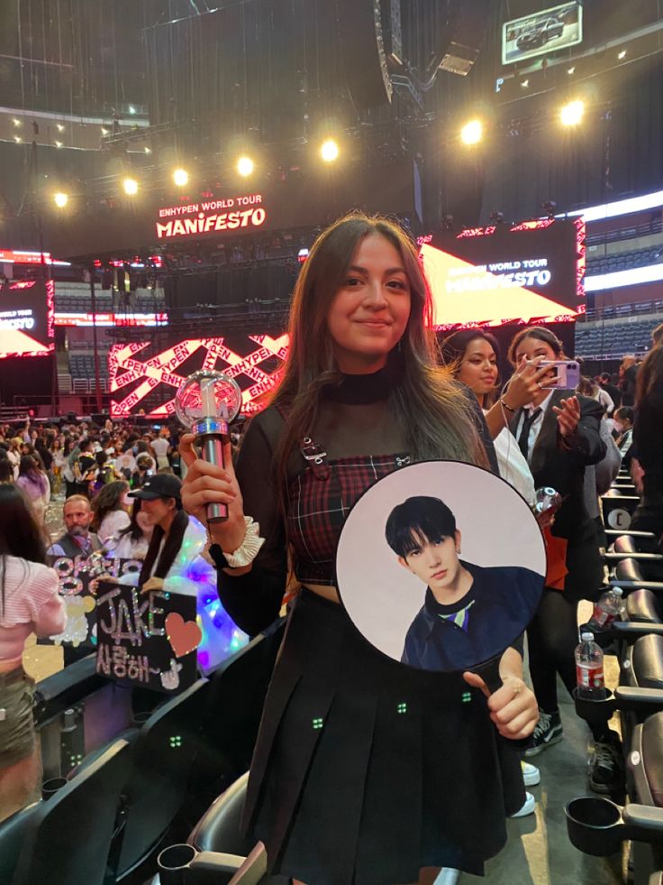 a woman is holding up a photo and posing for the camera in front of an audience