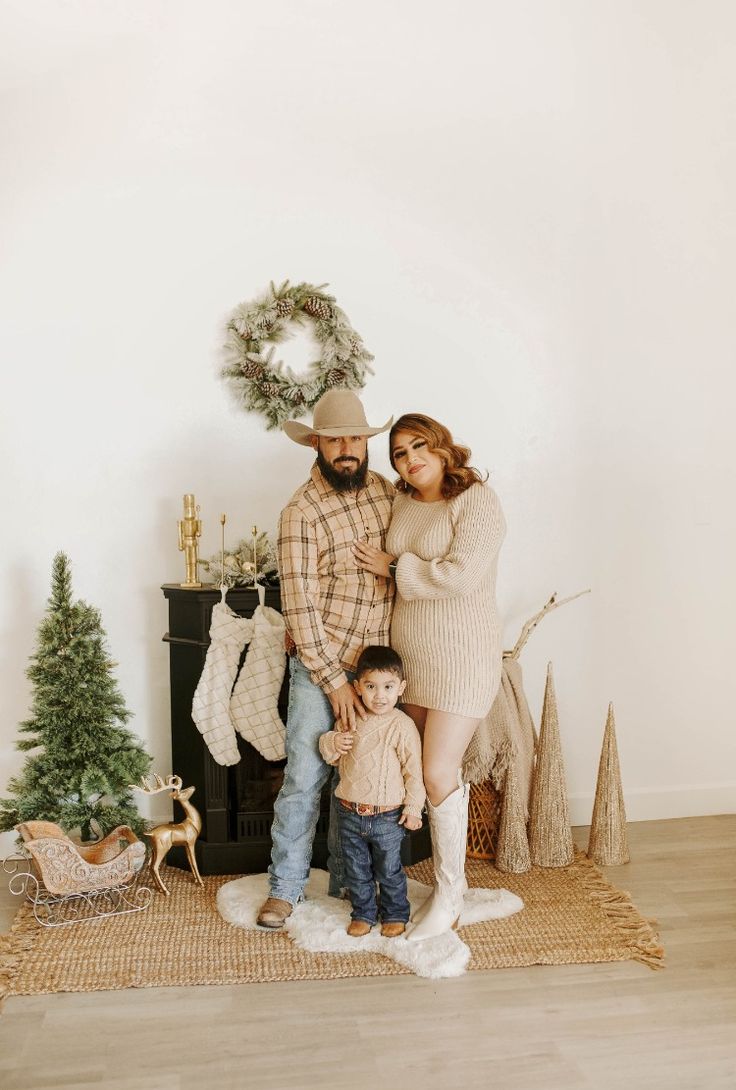 a man, woman and child standing in front of a christmas tree