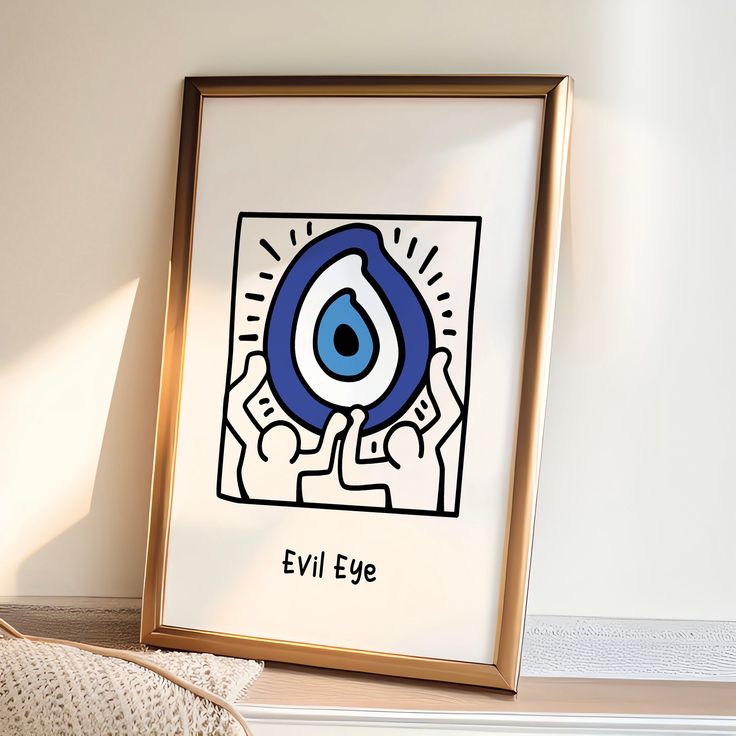 an evil eye framed in a gold frame next to a white wall with a pillow on it