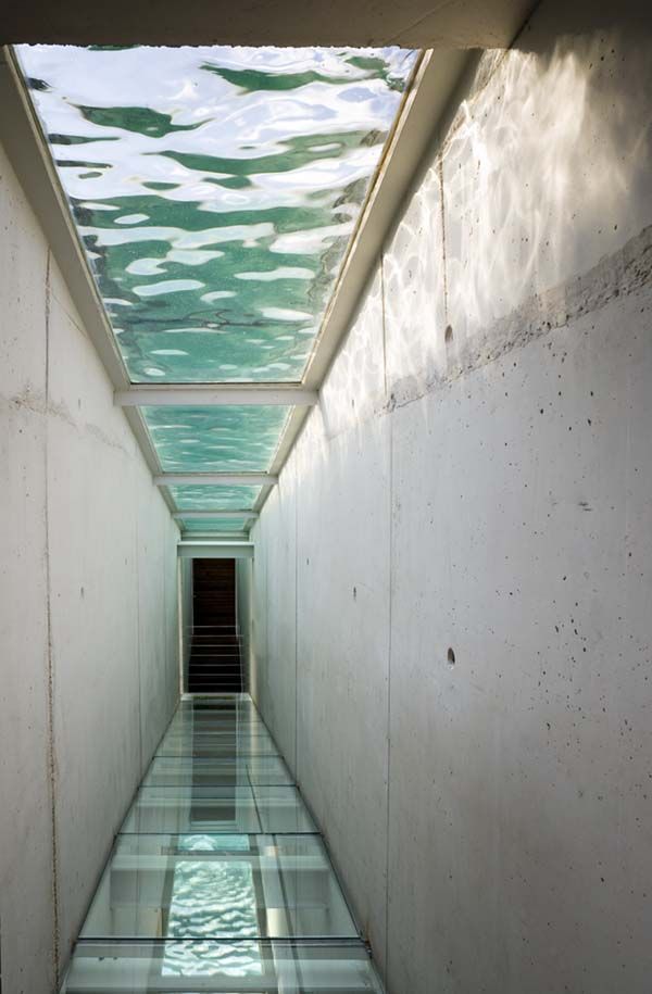 a long narrow hallway with water in the middle and light at the end on either side