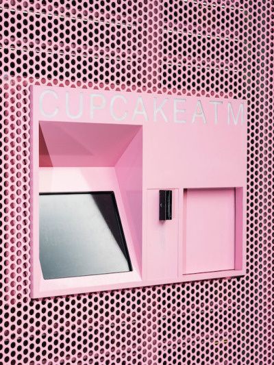 a pink cupcake atm machine sitting on top of a perfored metal wall