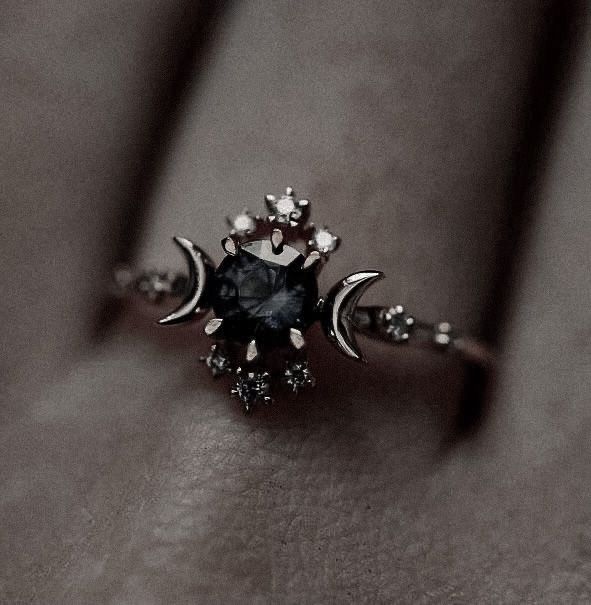 a black and white photo of a ring on someone's finger with the moon in the middle