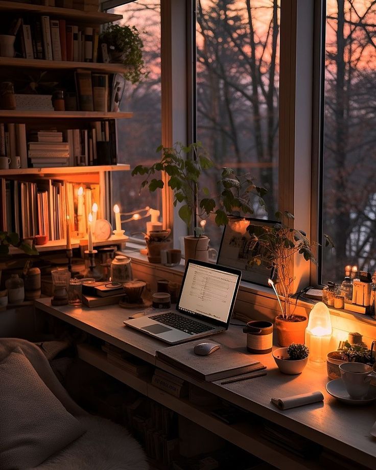 a laptop computer sitting on top of a wooden desk in front of a large window