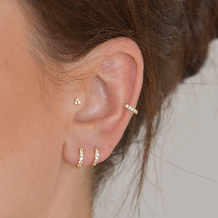 a close up of a person's ear wearing gold and diamond hooped earrings