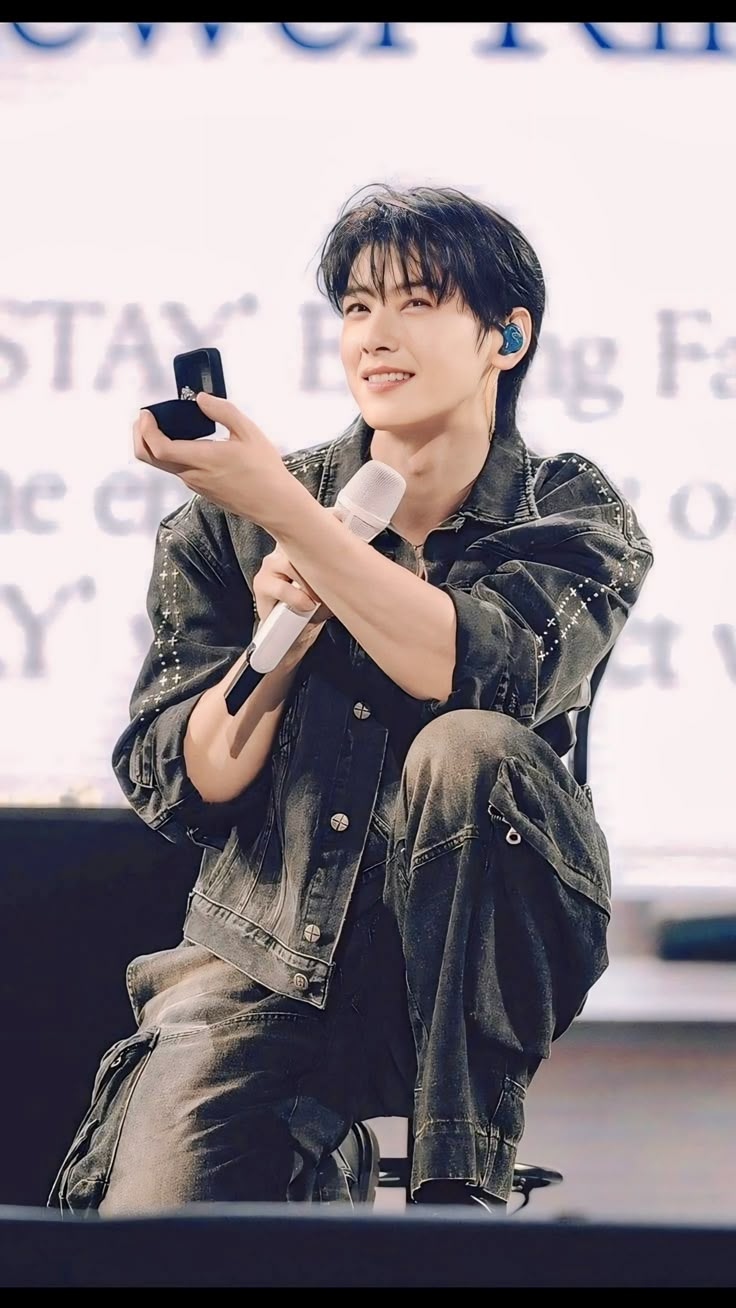 a young man sitting on top of a stage holding a remote control in his hand