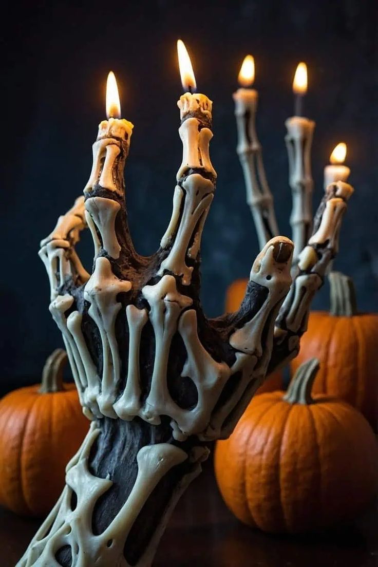 a skeleton hand holding candles in front of some pumpkins