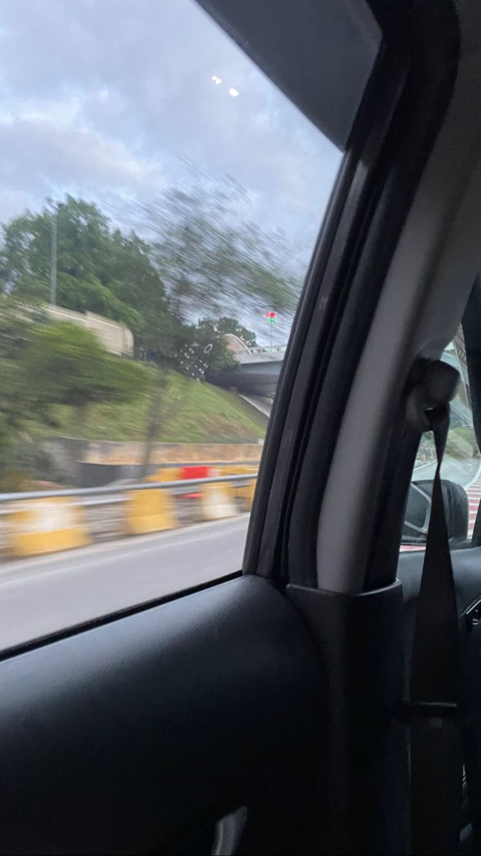 the view from inside a car driving down a highway with trees and buildings in the background