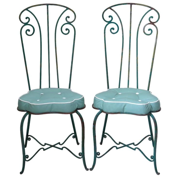 pair of wrought iron chairs with blue upholstered seat cushions and white piping