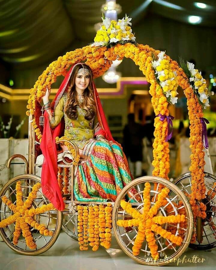 a woman sitting on top of a horse drawn carriage covered in flowers and garlands