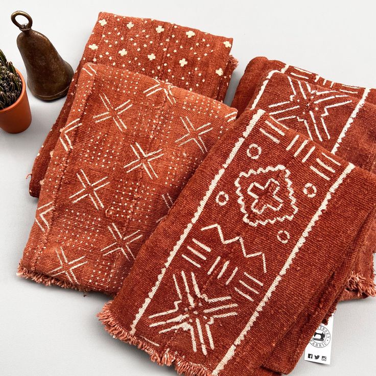 three red towels with white designs on them next to a potted plant and spoon