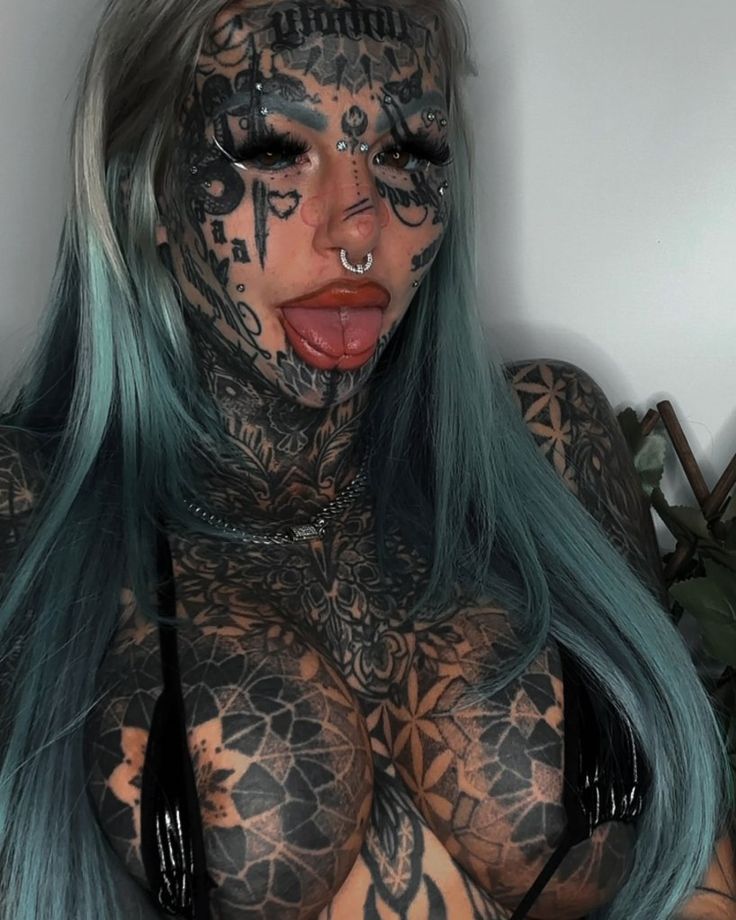 a woman with green hair and tattoos on her body is posing for the camera,