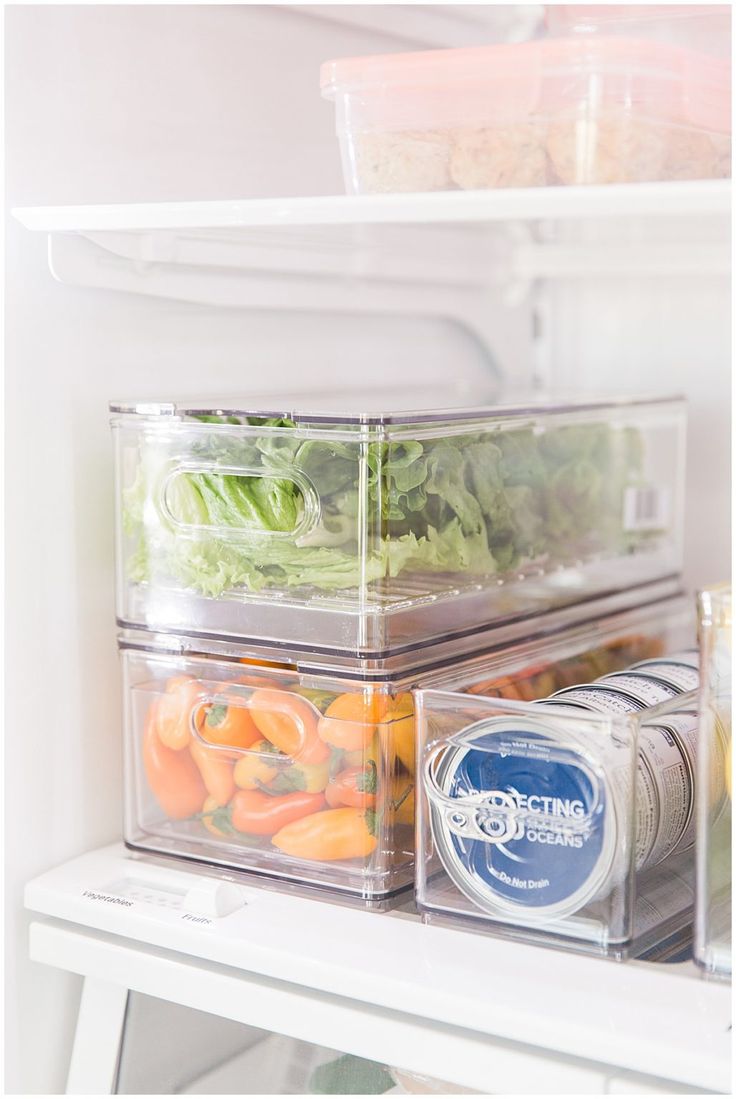 an open refrigerator door with food in containers on the bottom shelf and vegetables inside it