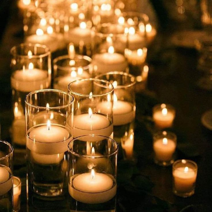 many lit candles are lined up on a table