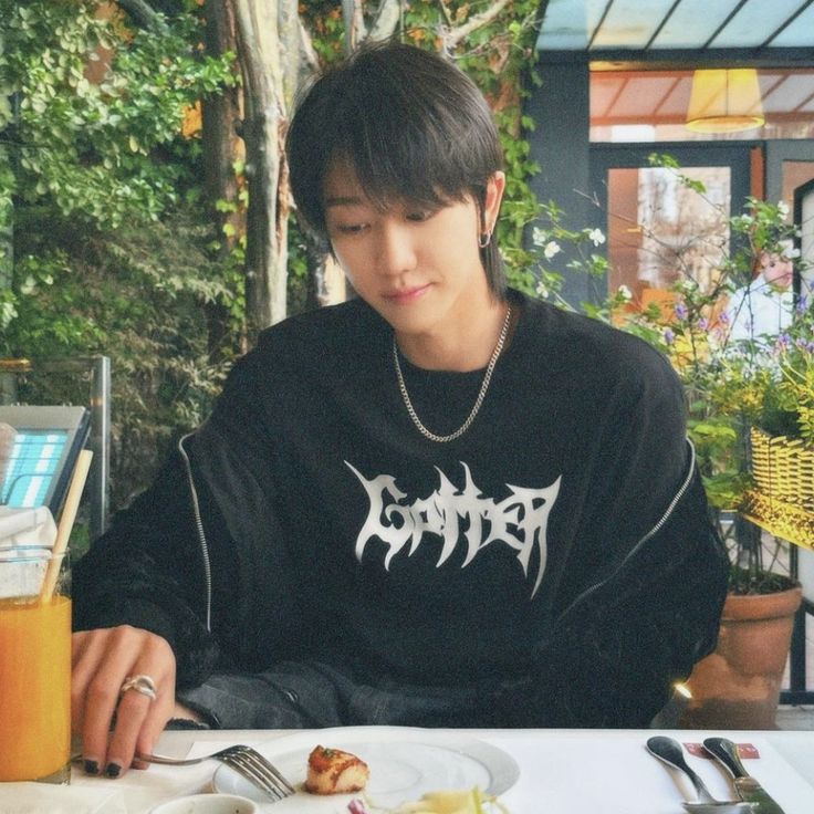 a young man sitting at a table in front of a plate with food on it