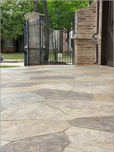 a stone patio with an iron gate in the background