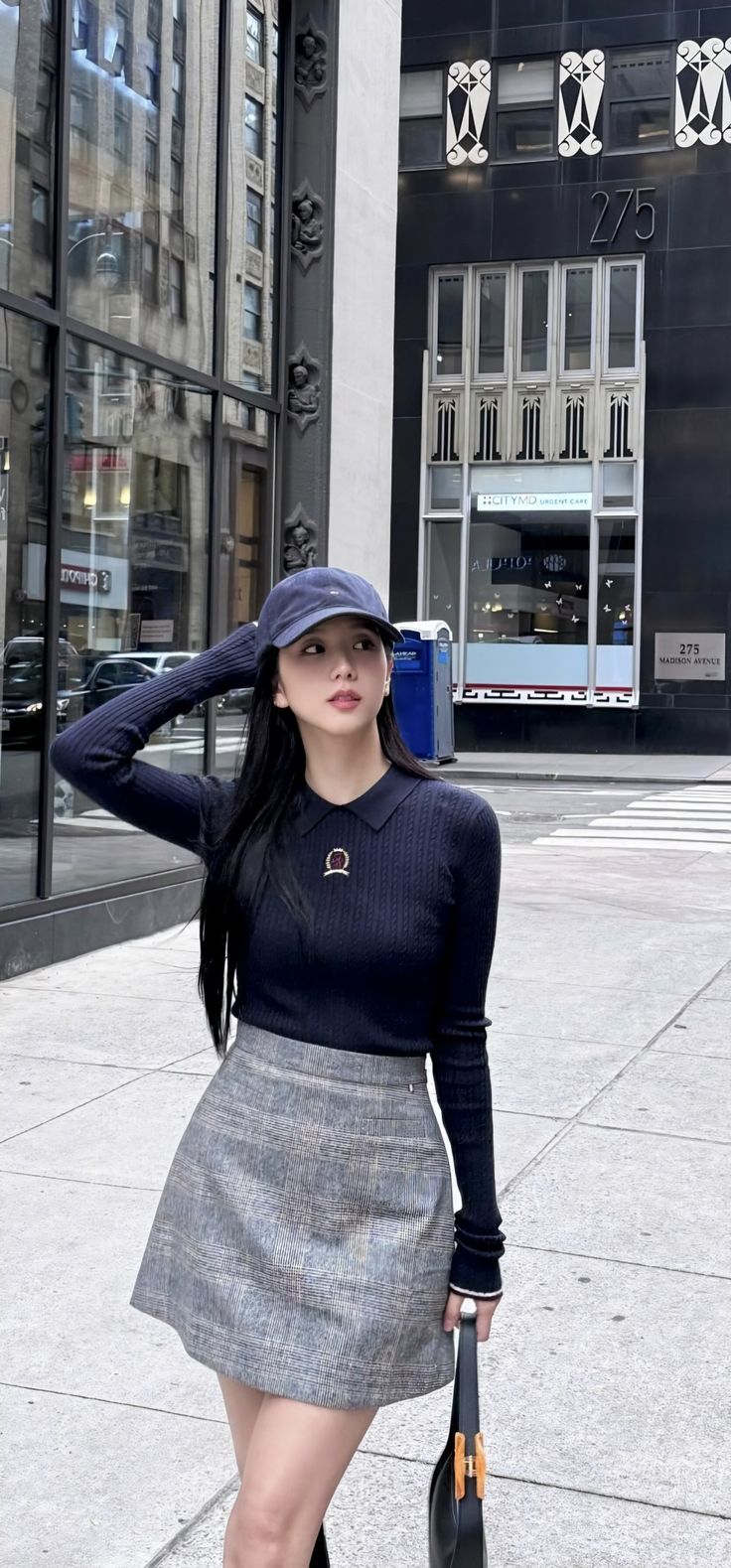 a woman is walking down the street with a hat on her head and holding a bag