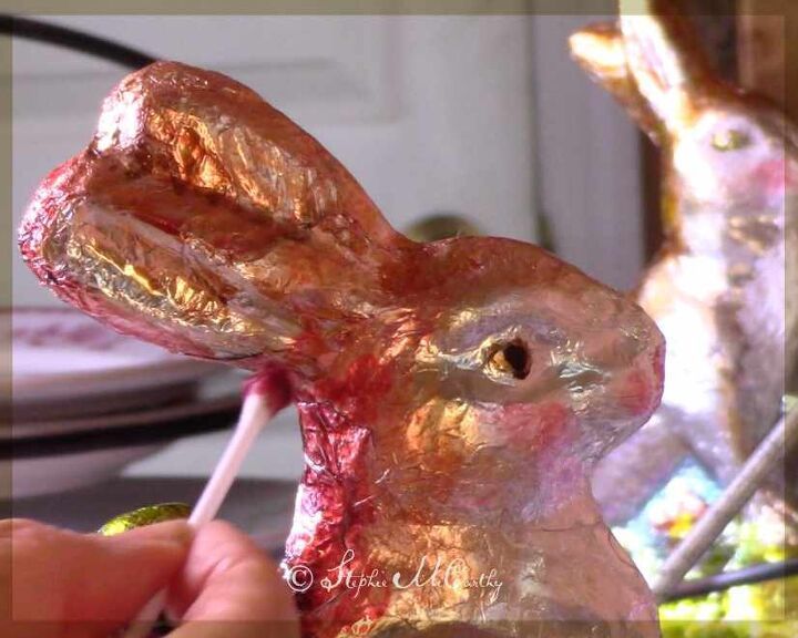 a person holding a candy bar in front of a fake bunny rabbit head on a table