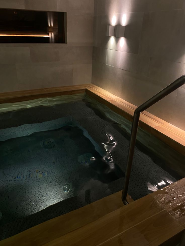 an indoor jacuzzi is lit up in the dark room with lights on it