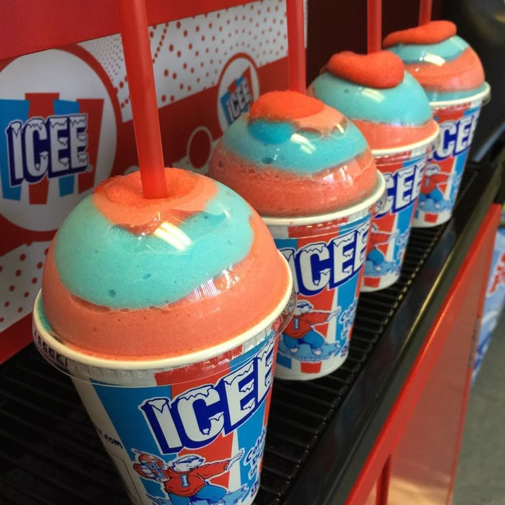 three ice cream cups are lined up on the shelf in front of an ice cream machine