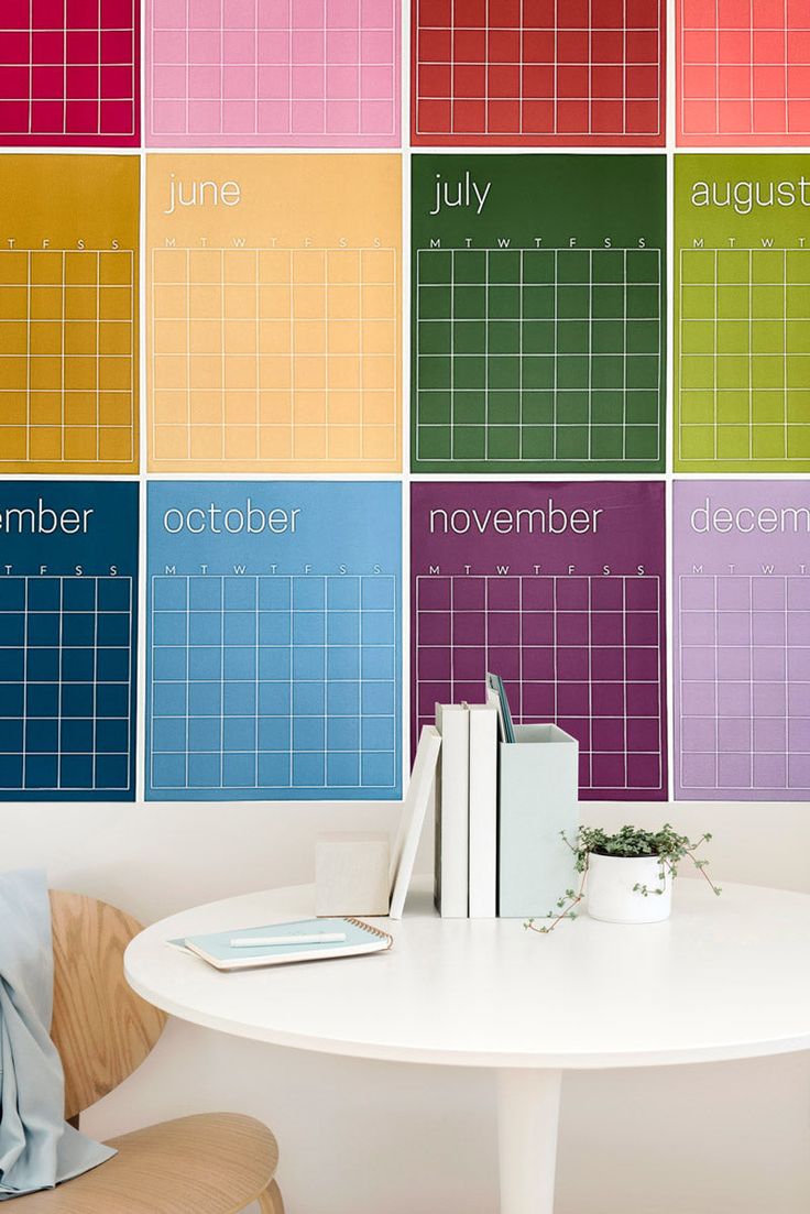 there is a table with books on it in front of the colorful calendar wallpaper