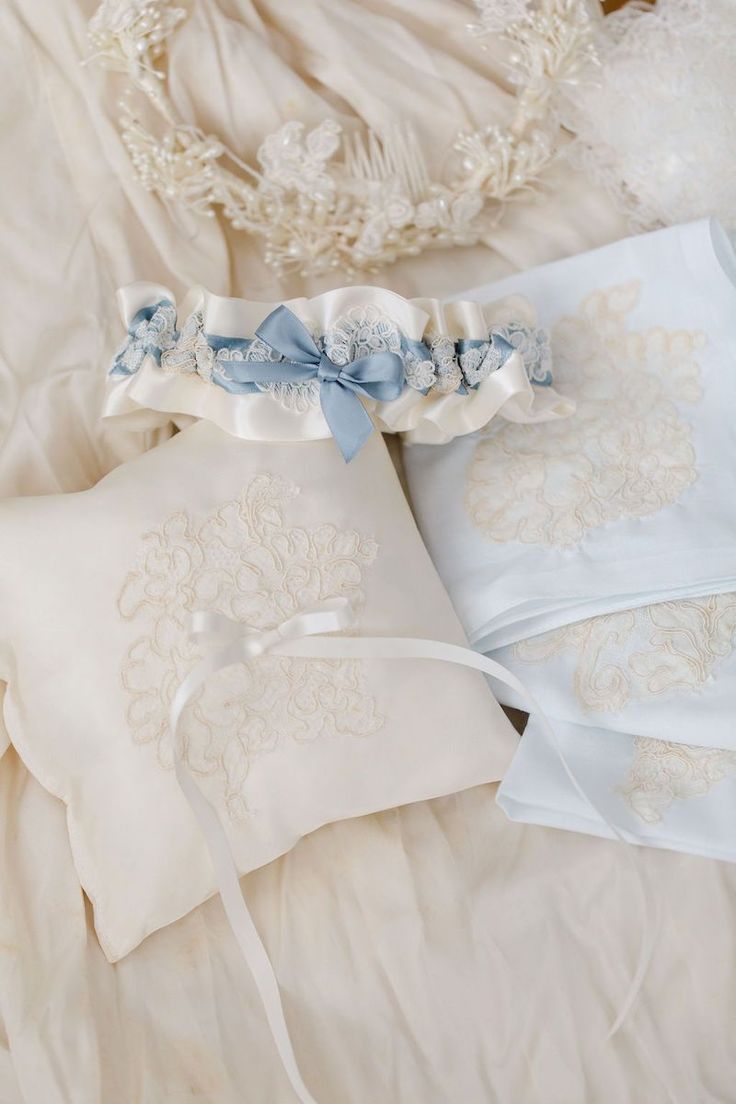 two wedding garters are laying on top of a white bed sheet with blue ribbons