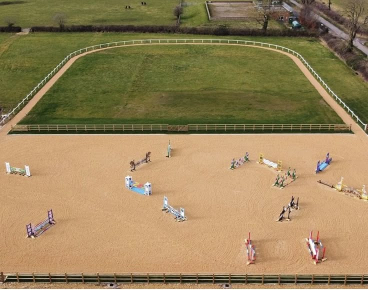 an aerial view of a horse track with horses on it and people standing around in the sand