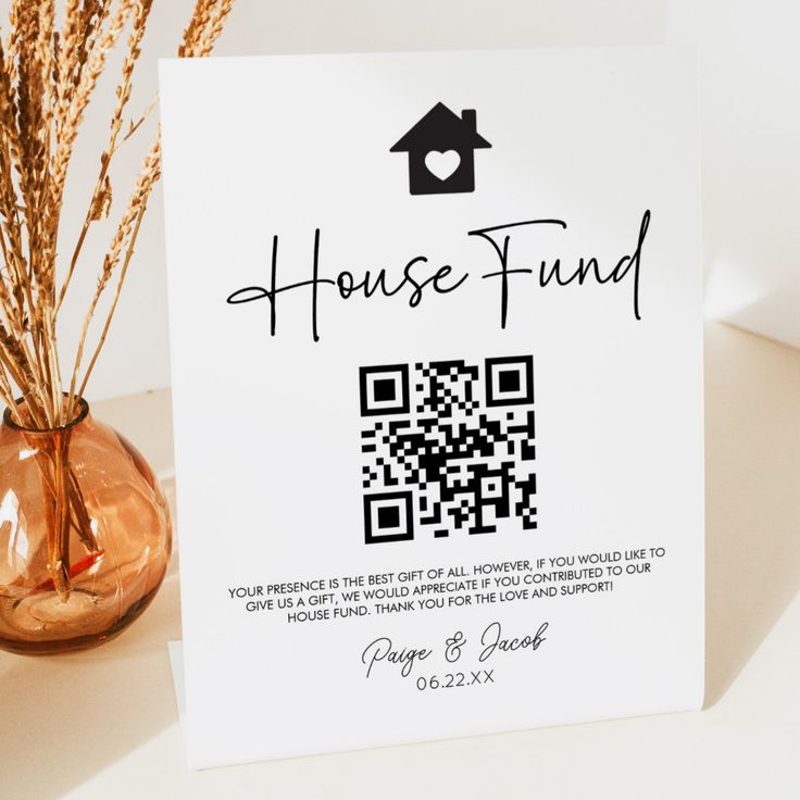 a house fund card sitting on top of a table next to a vase filled with flowers