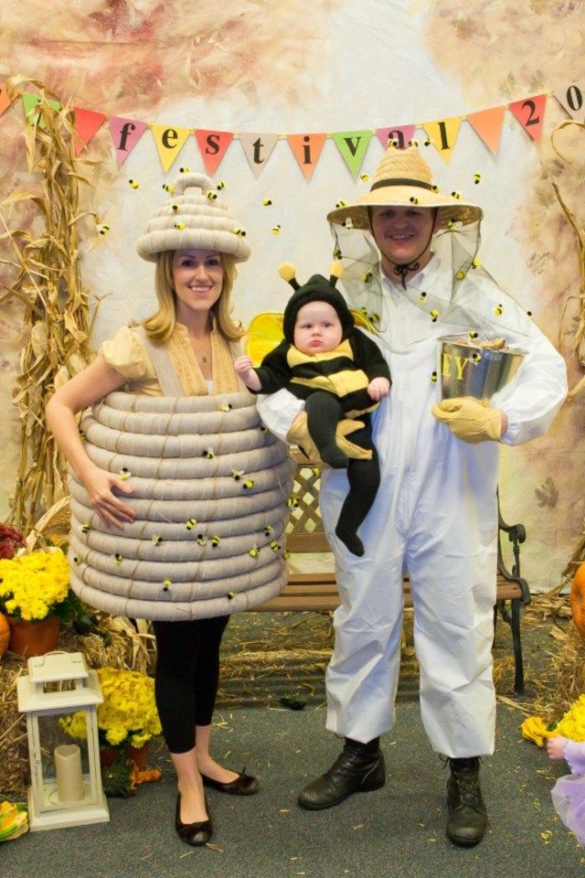 two people in costumes standing next to each other and one holding a baby on his chest