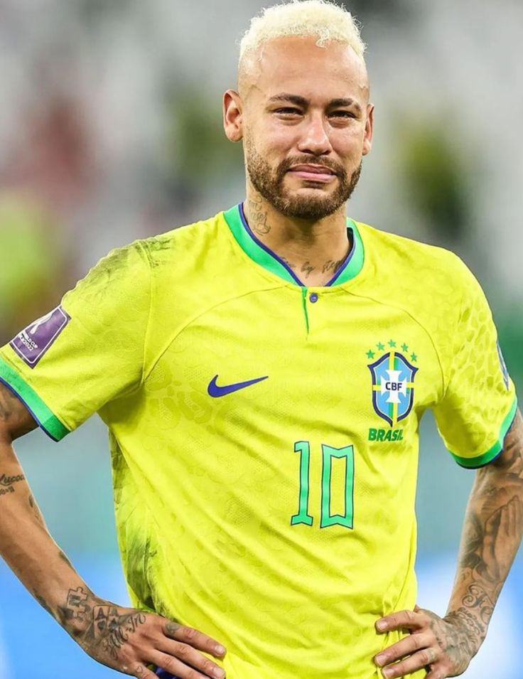 a soccer player with his hands on his hips wearing a yellow shirt and blue shorts