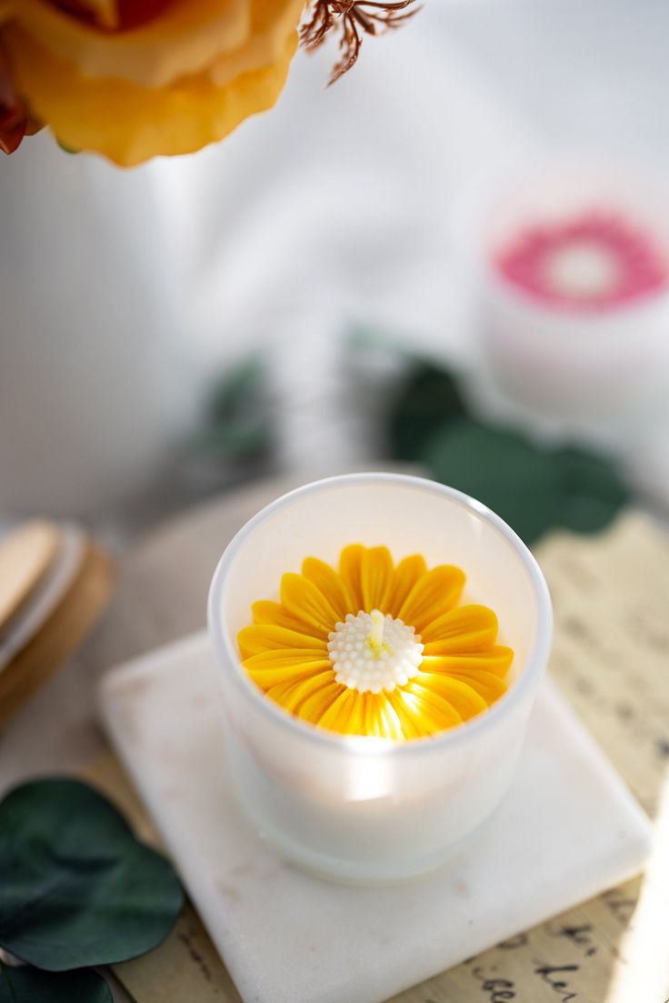 a yellow flower in a small white bowl