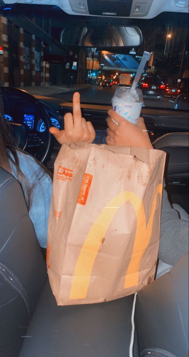 a woman sitting in the back seat of a car holding a bag