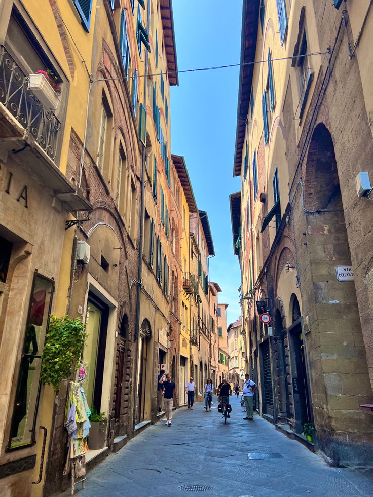 people are riding bicycles down an alleyway in the old part of town on a sunny day