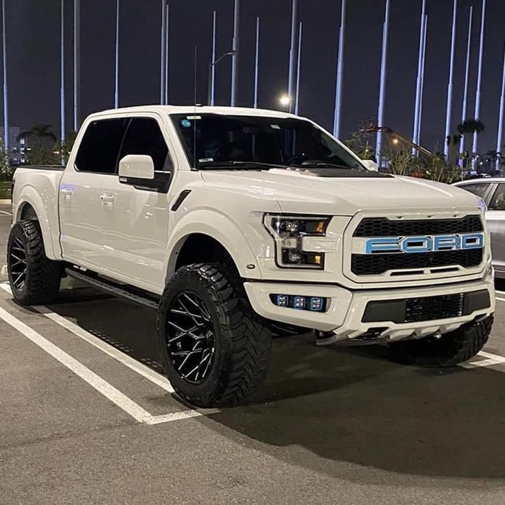 a white pickup truck parked in a parking lot at night with its lights turned on