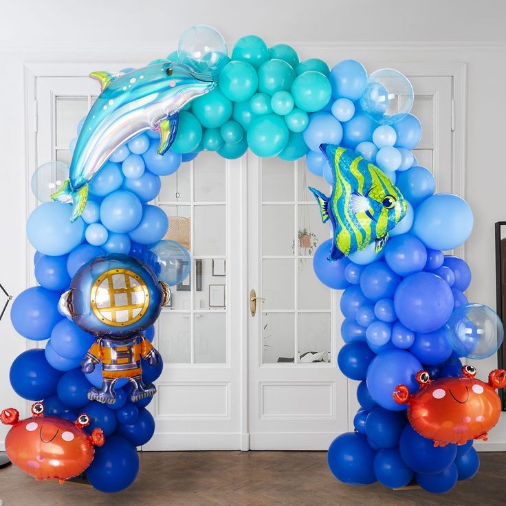 a balloon arch decorated with blue and orange balloons, an underwater diver helmet and fish