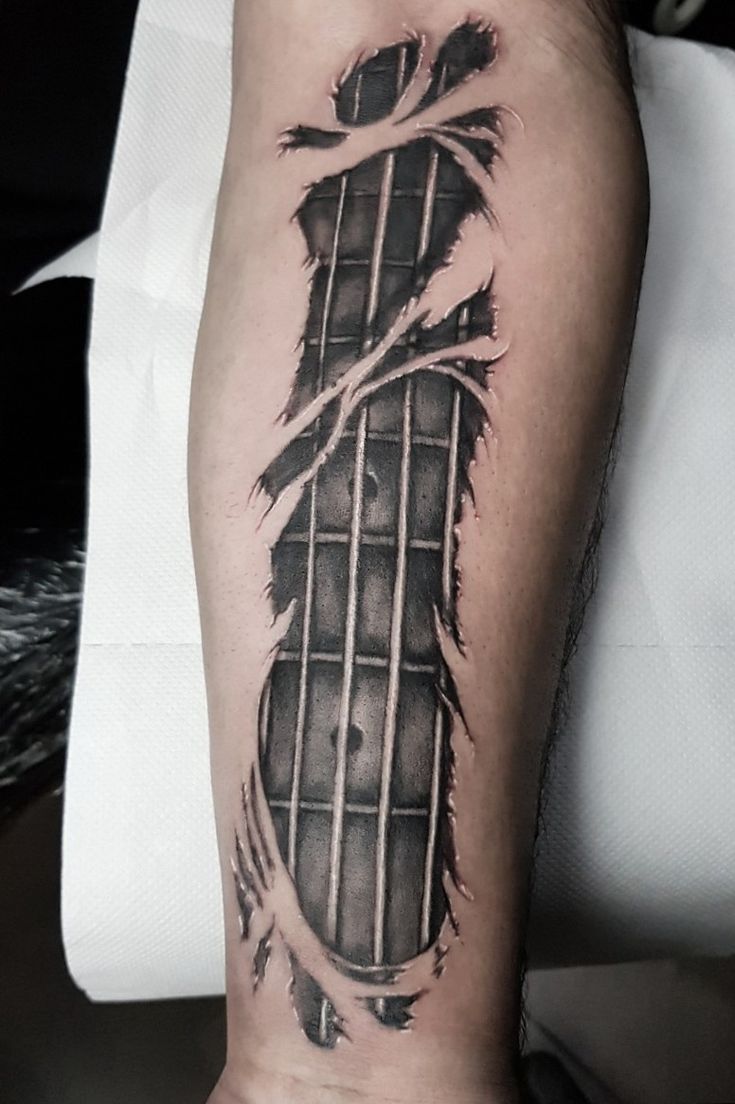 a man's arm with a guitar tattoo on the left side of his leg