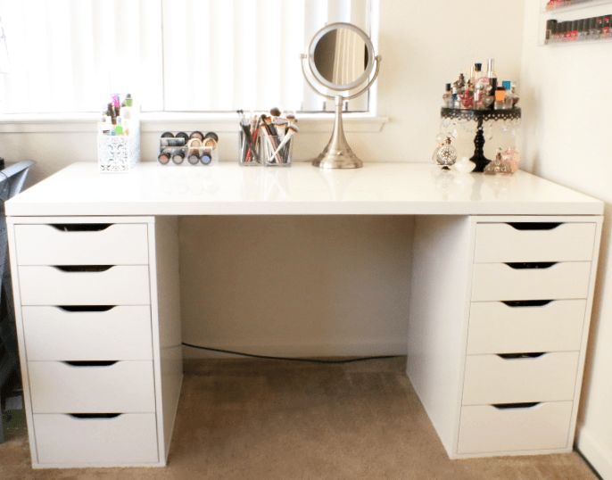 a white desk topped with lots of drawers under a window next to a dresser and mirror