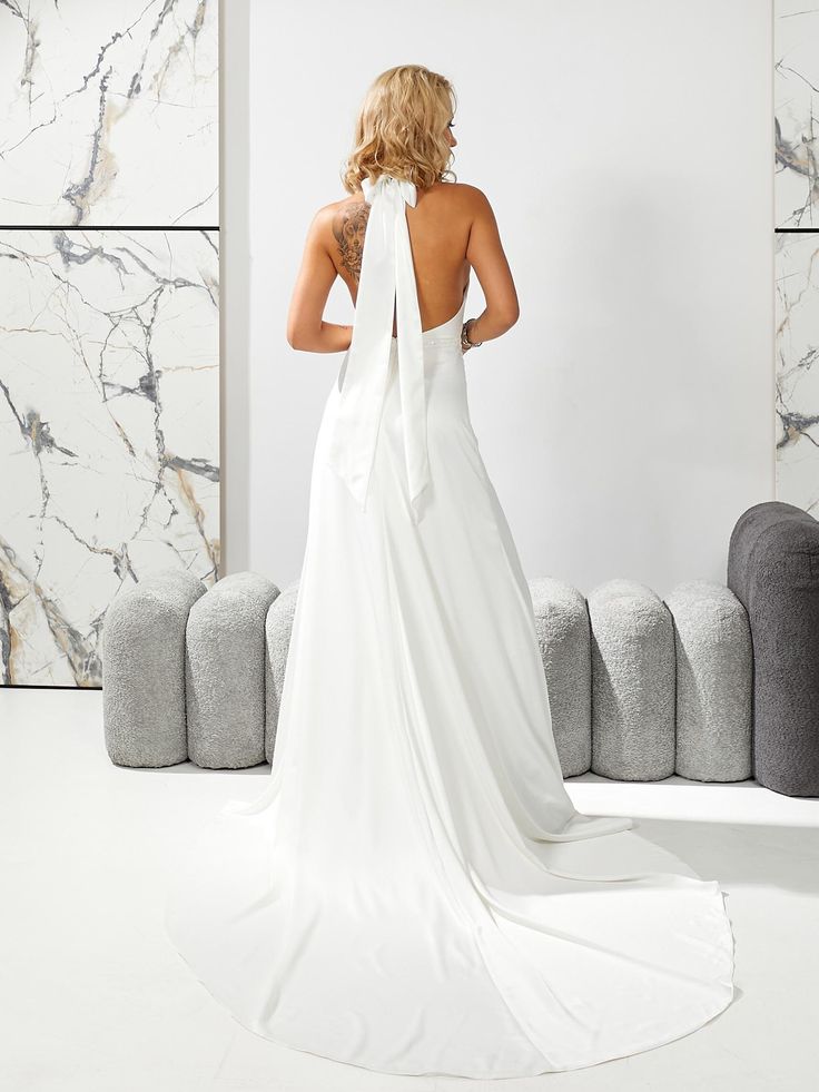 a woman in a white dress is looking at the back of her wedding dress,