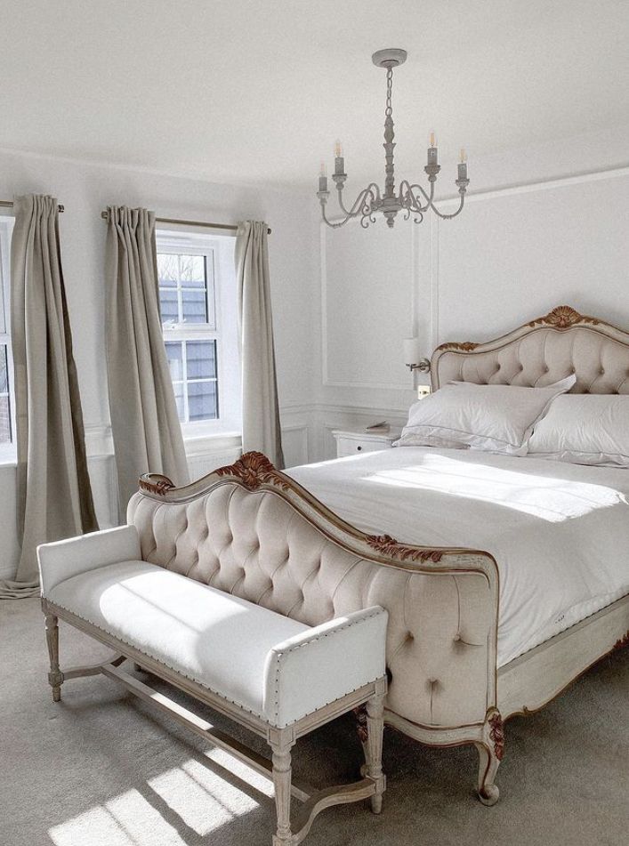 a bedroom with a bed, chair and chandelier