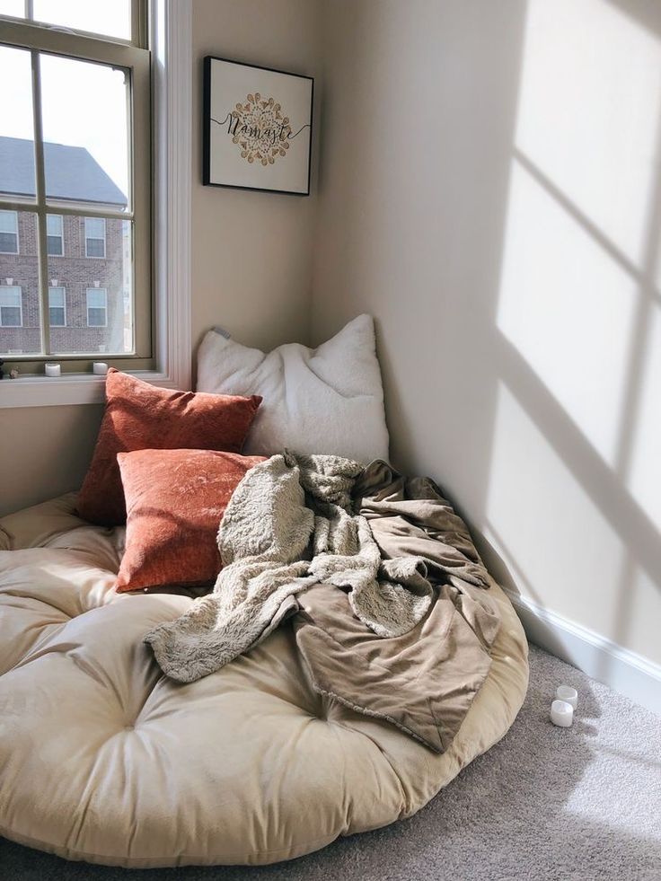 an unmade bed in the corner of a room with pillows and blankets on it