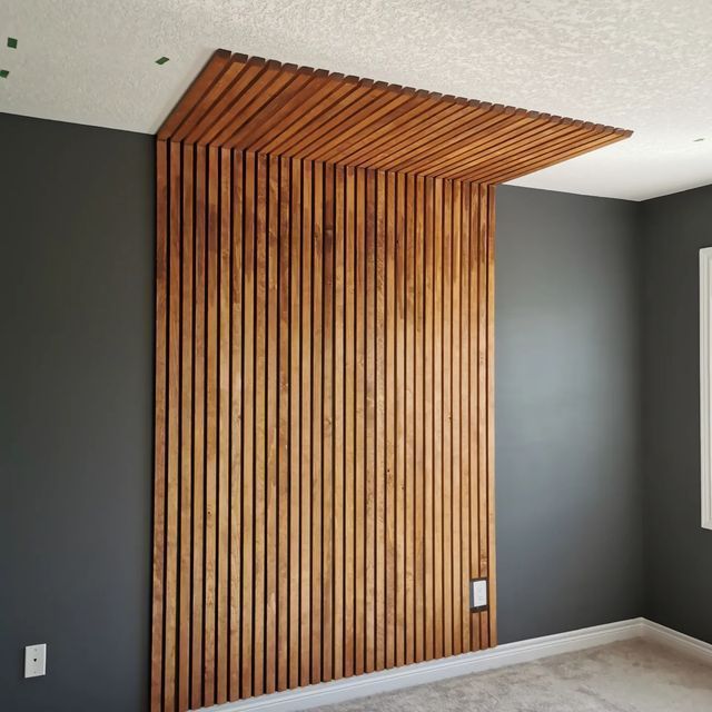 an empty room with grey walls and wood slats on the wall, in front of a window