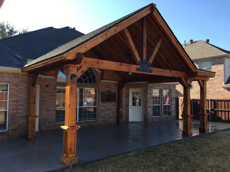 a wooden covered patio in front of a brick building