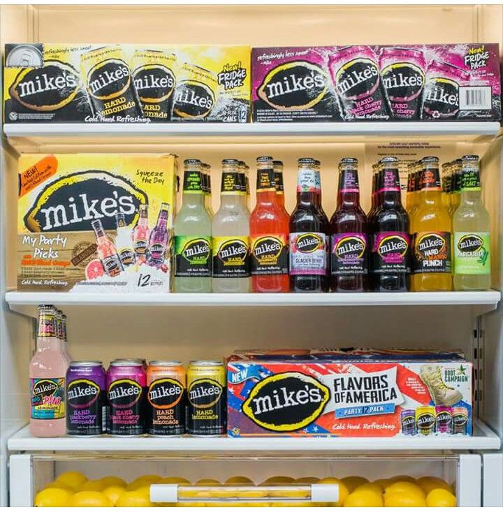 an assortment of drinks and juices on shelves in a refrigerator with the door open