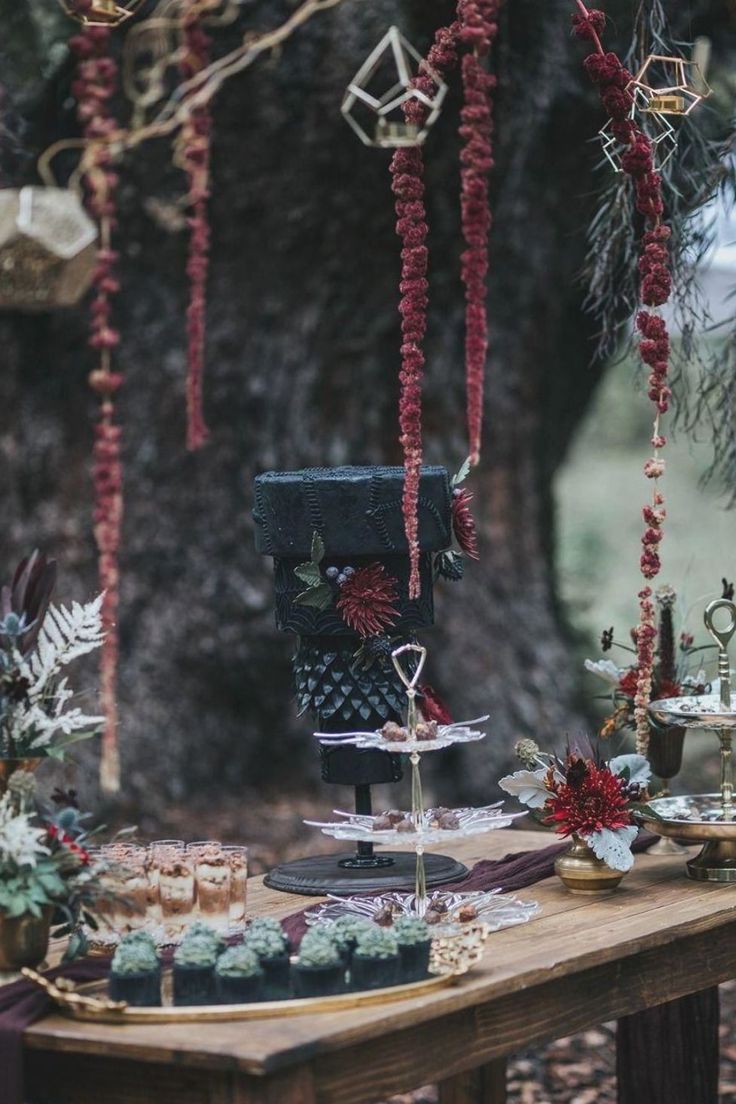 a table topped with cakes and cupcakes under a tree