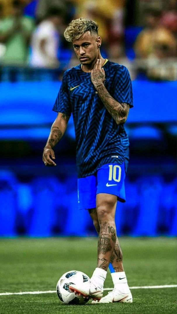 a man with tattoos standing next to a soccer ball