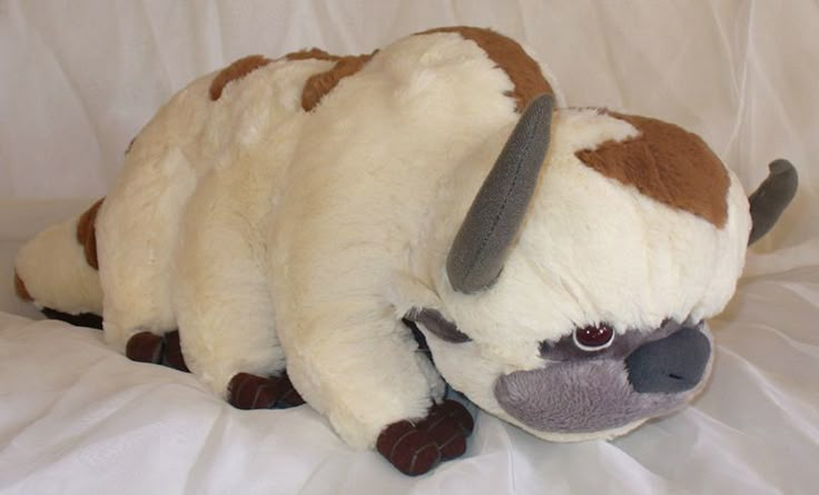 a stuffed animal that is laying down on a white sheet with it's eyes open