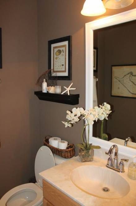 a white toilet sitting next to a bathroom sink under a mirror with lights on it