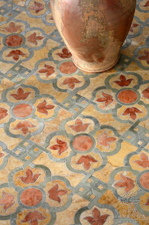 a vase sitting on top of a tiled floor next to a rug with flowers and leaves